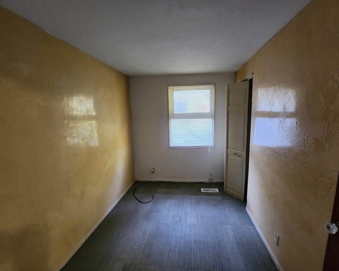 Bedroom before renovation with stained walls and worn carpet.