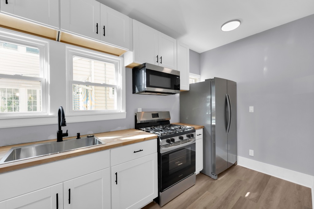 Kitchen after renovation: butcher block counters, black faucet, stainless range and refrigerator.