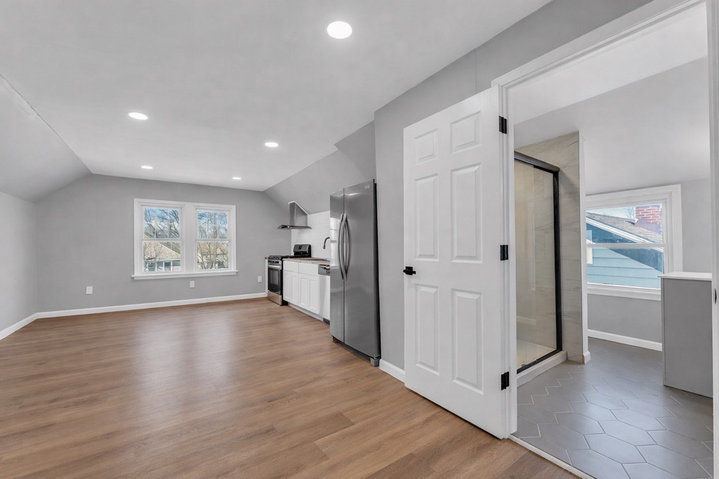 Upstairs unit after renovation: open living area with kitchen wall and bathroom under the sloped ceiling.