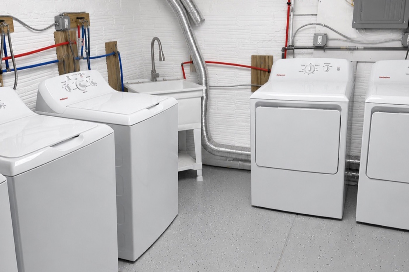 Basement laundry after renovation: painted block walls, epoxy floor, new washers and dryers, utility sink, glass-block window.