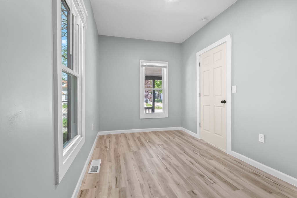 Main-level room after renovation: grey walls, new plank flooring, bright window.