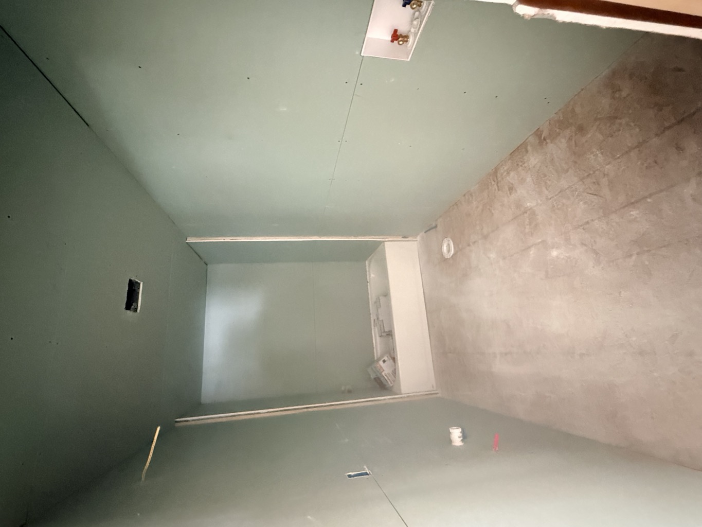 Bathroom with moisture-resistant green board on the walls and ceiling and a new tub set in place.