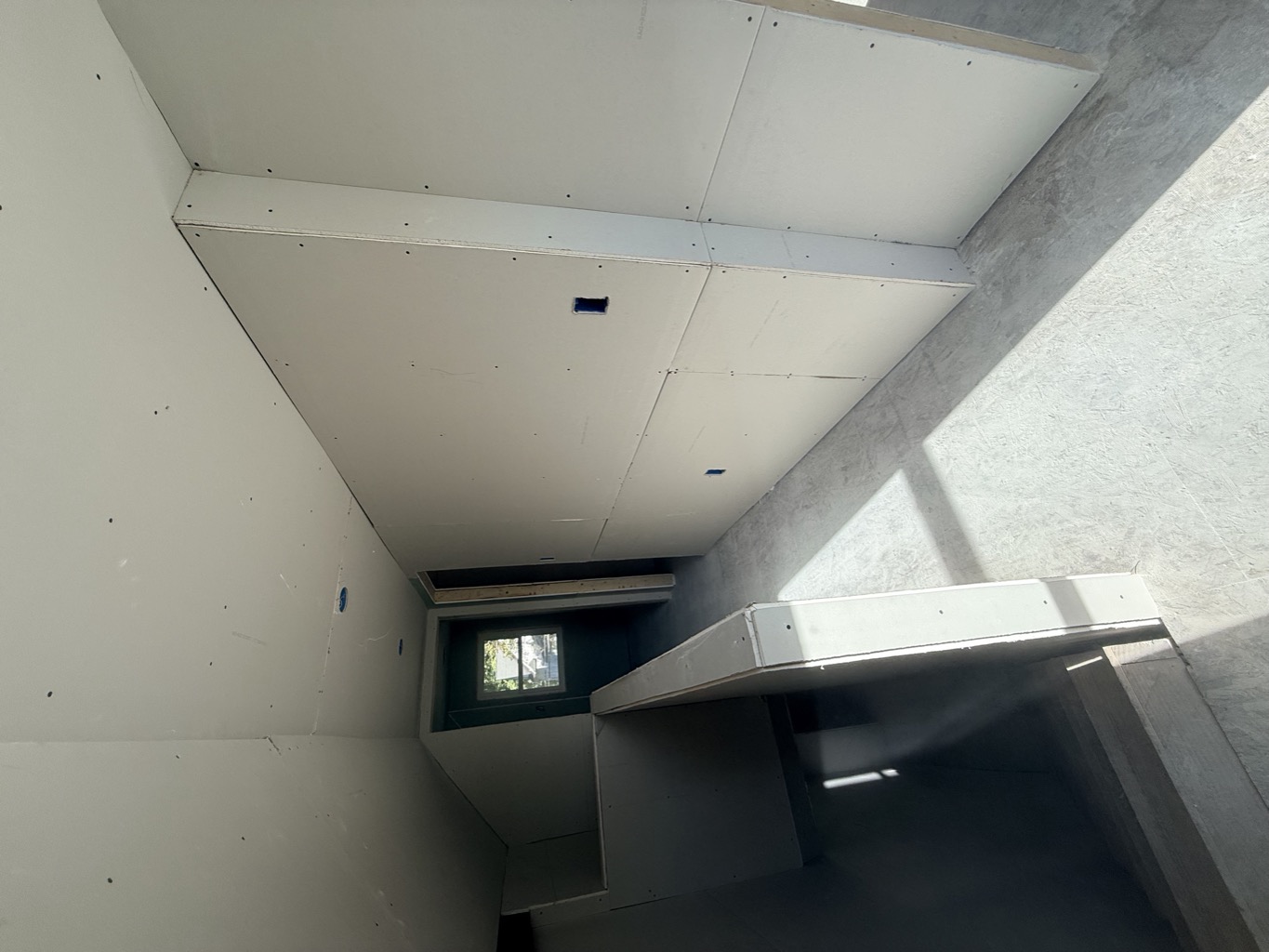 Upstairs landing and hallway with new drywall on the walls and sloped ceiling.